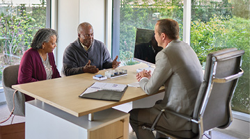 man and woman sitting at a desk and meeting with a financial professional